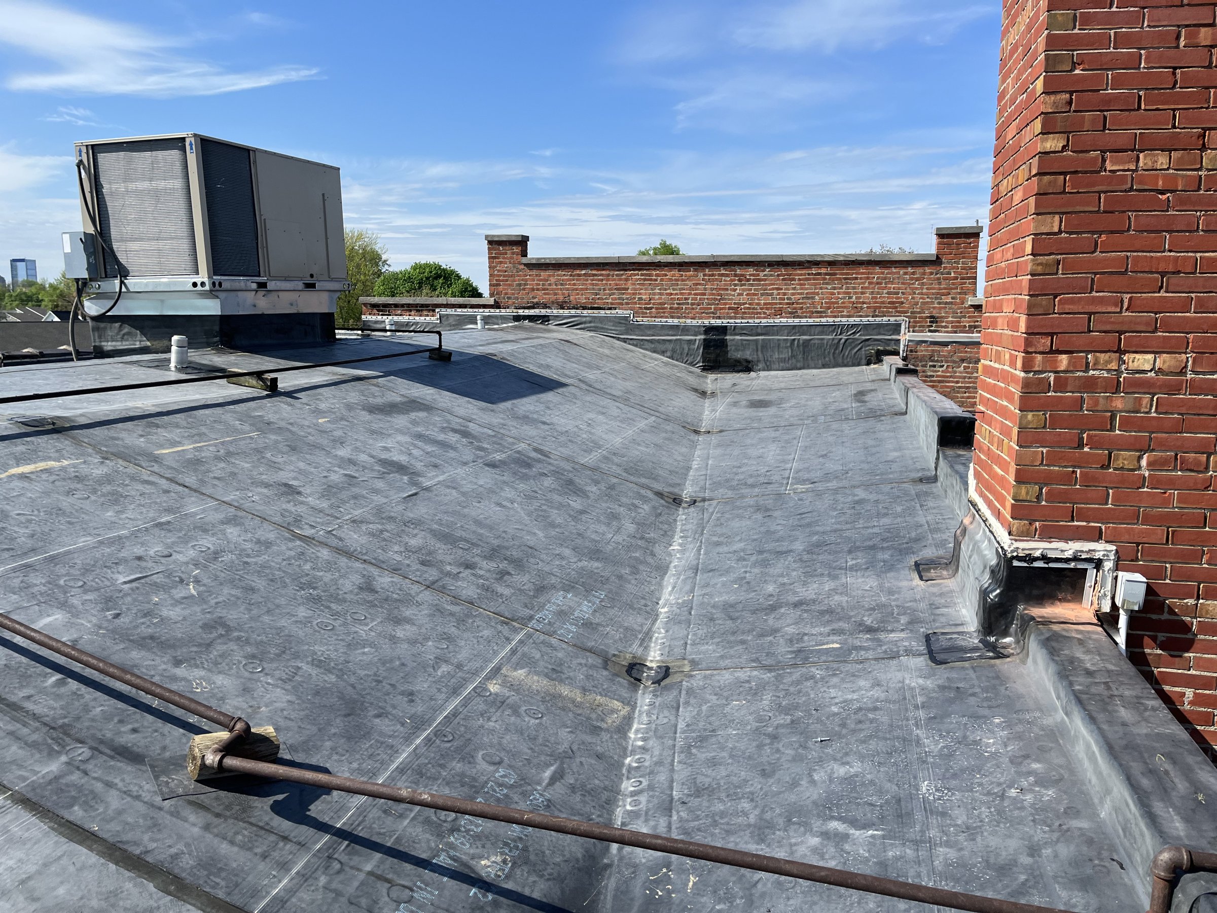 Black EPDM rubber roof with a rooftop HVAC unit and brick parapet walls